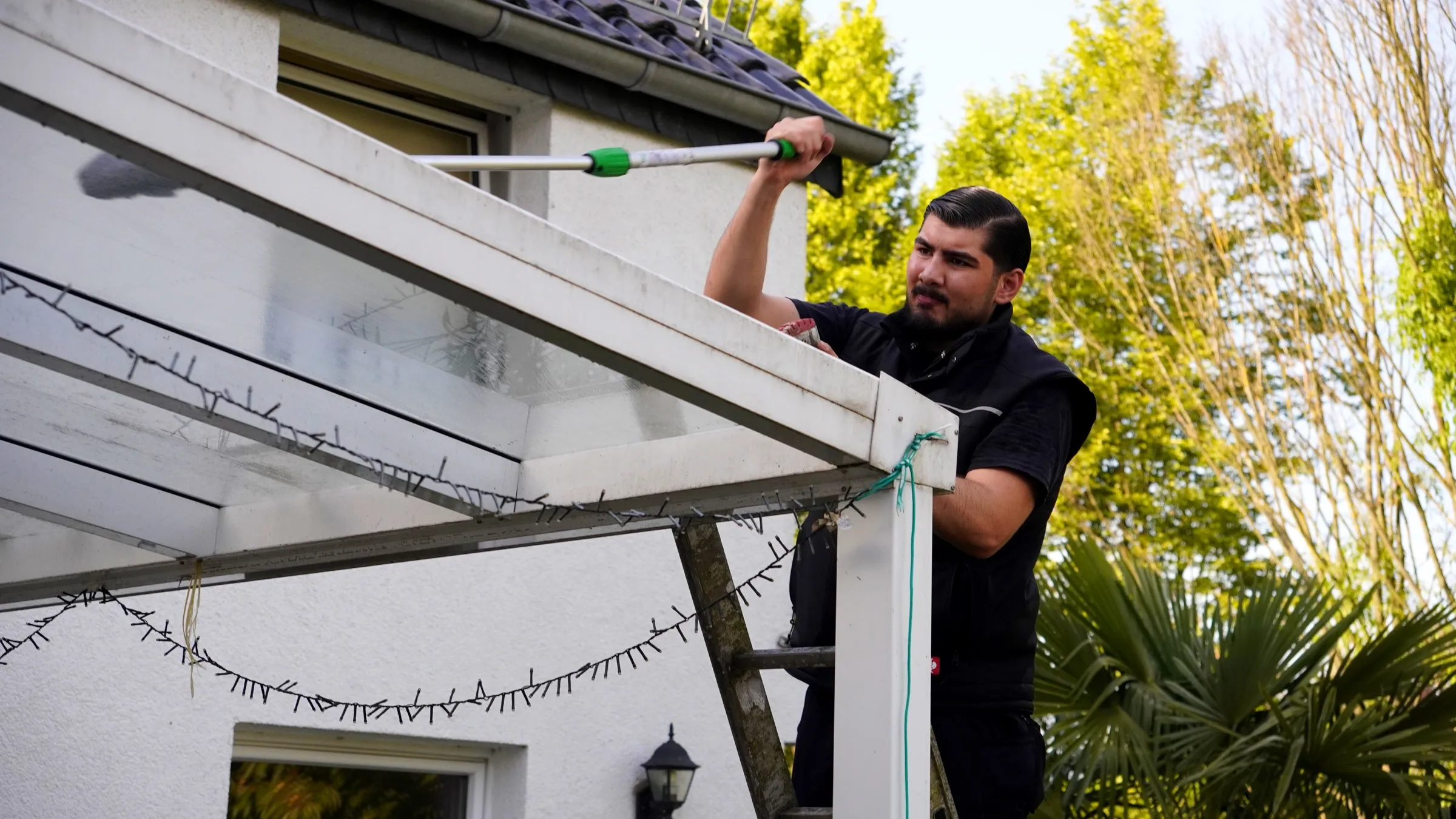 Mitarbeiter von Koç Dienstleistungen reinigt eine Terrassenüberdachung in Bonn
